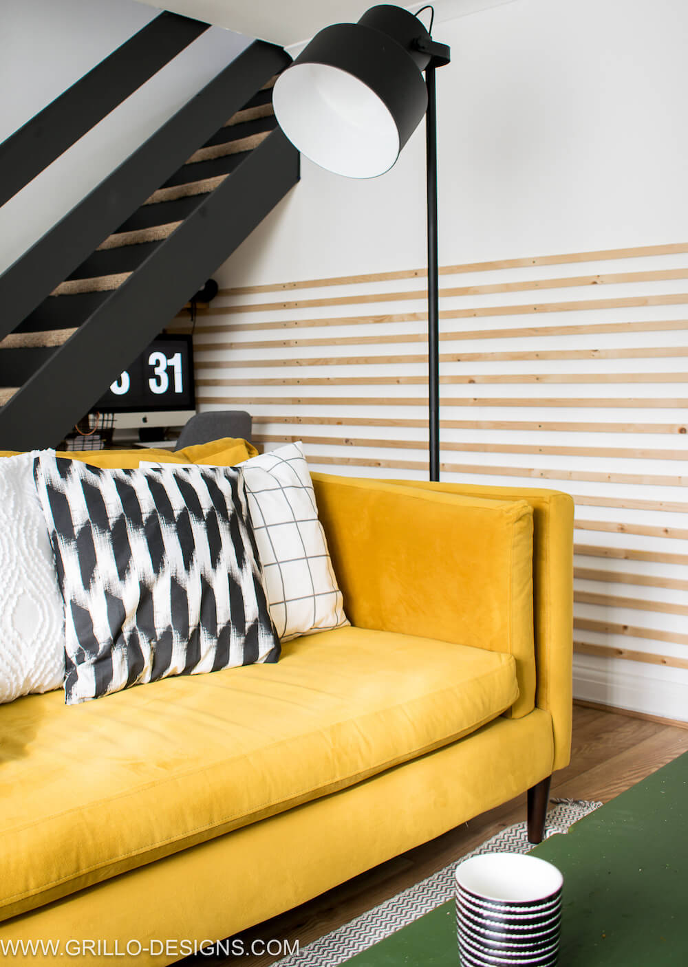Large franke floor lamp positioned at the side of the yellow sofa