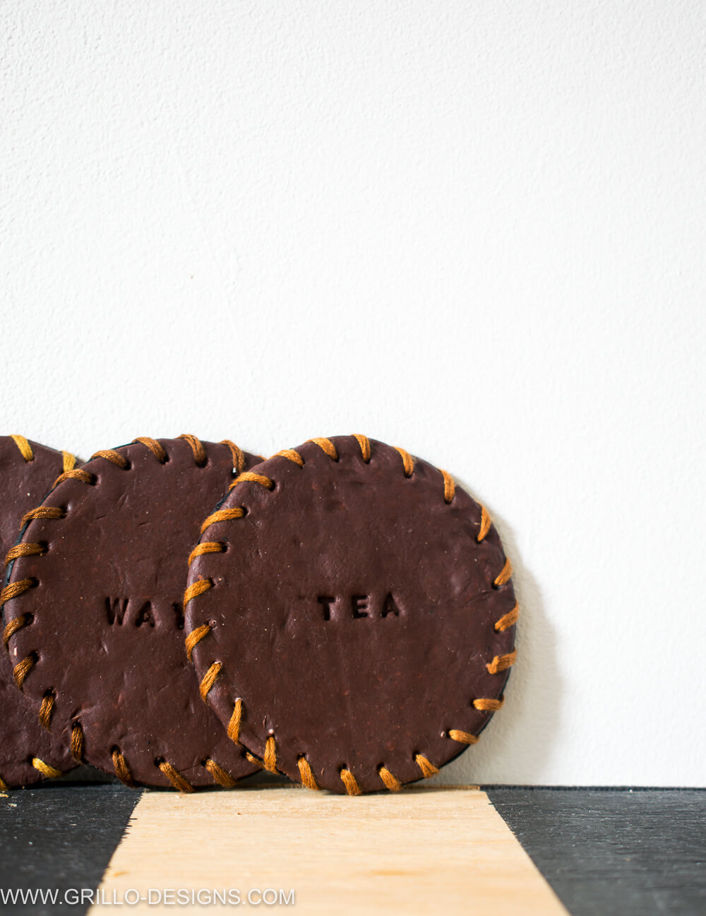 Image of three leather coasters leaned up against the wall 