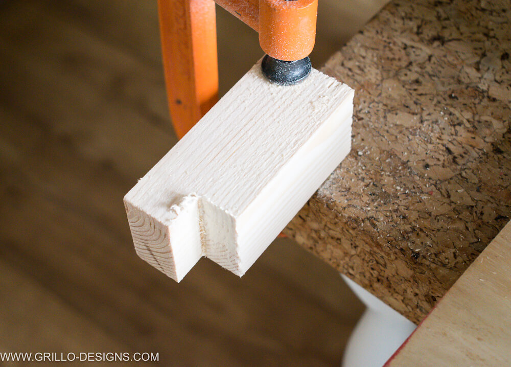 Wooden feed clamped to a cork board table and small 90 degree angle cut from the wood