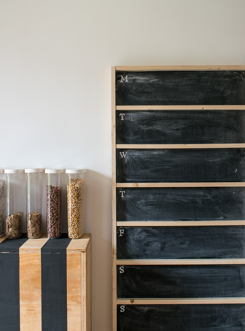 Diy chalkboard menu leaning against the wall next to a striped cabinet with cereal atop 