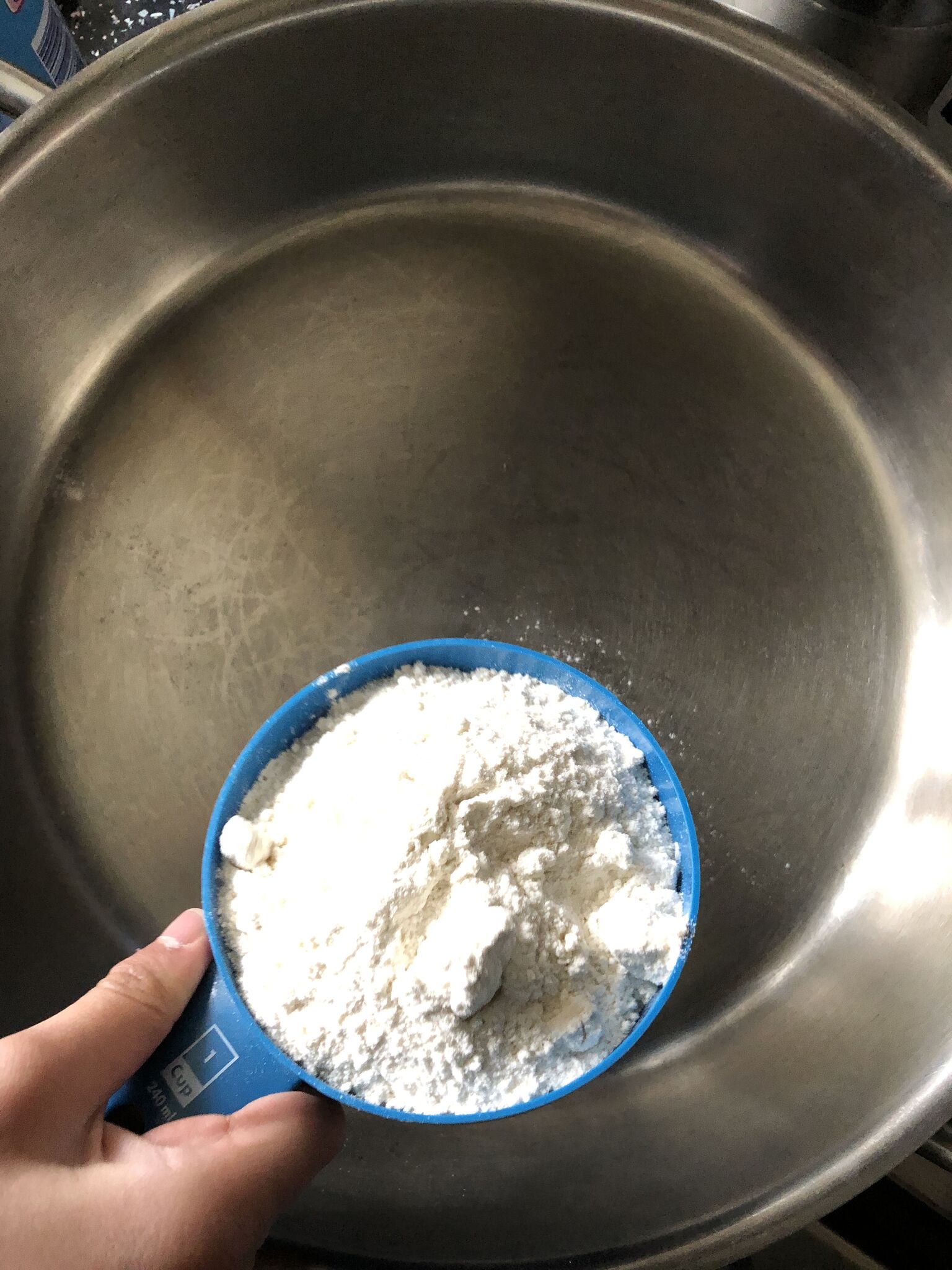 Putting a cup of flour into a heated pan 