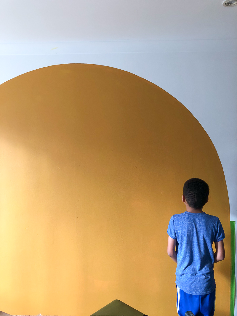 Boy standing in front of mustard painted arch in awe