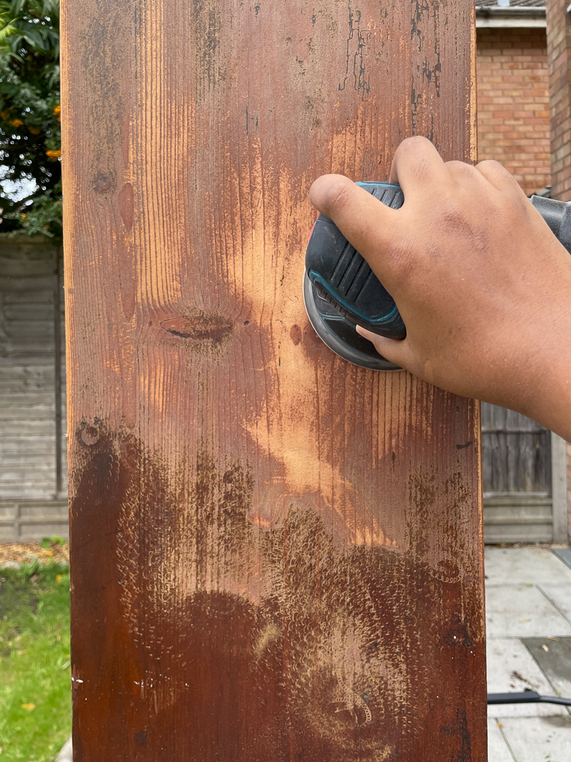 Image of my hand sanding the side of the vintage cabinet with an orbital sander 