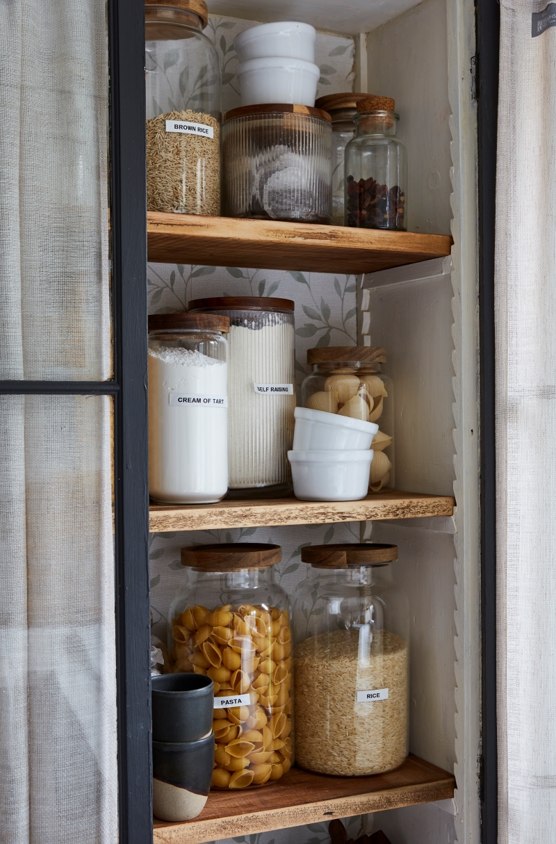 Close up image of interior of pantry cabinet jars of pasta and baking goods.