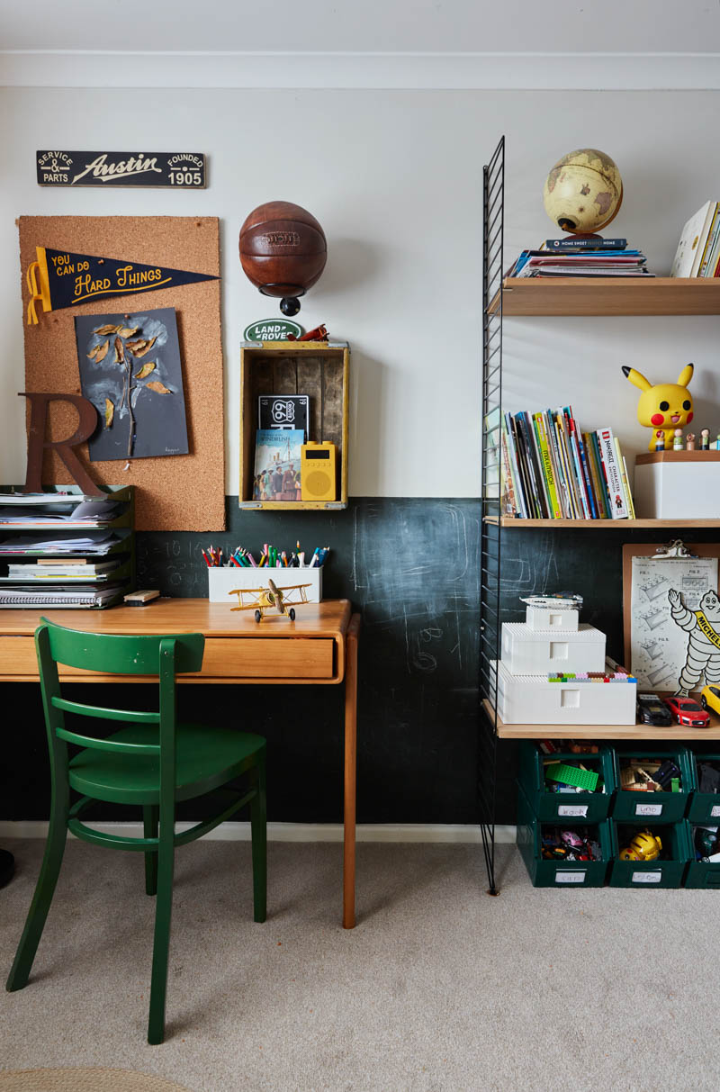desk area in travel themed boy's bedroom with wooden desk, green chair, shelving on the wall.