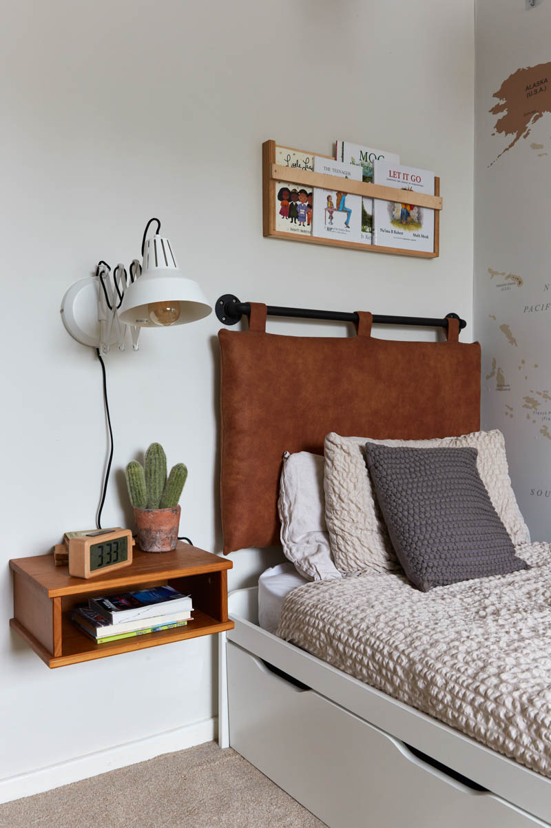 Bed with DIY headboard, floating side table and lamp with book rack above bed in boy's bedroom