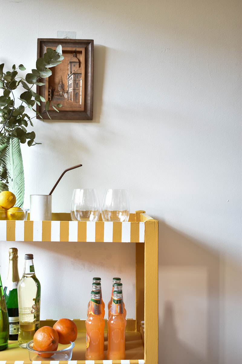 completed bar cart styled with glasses, beverages, and greenery