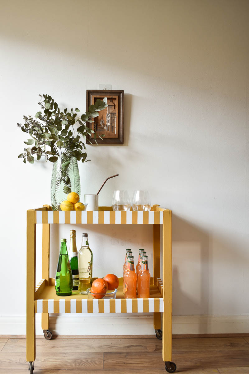 completed bar cart styled with glasses, beverages, and greenery