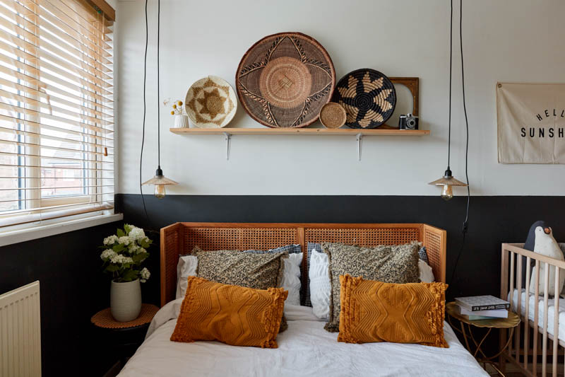 image of parent's bed with blue painted half wall accent, and decor in neutrals and browns with lots of texture