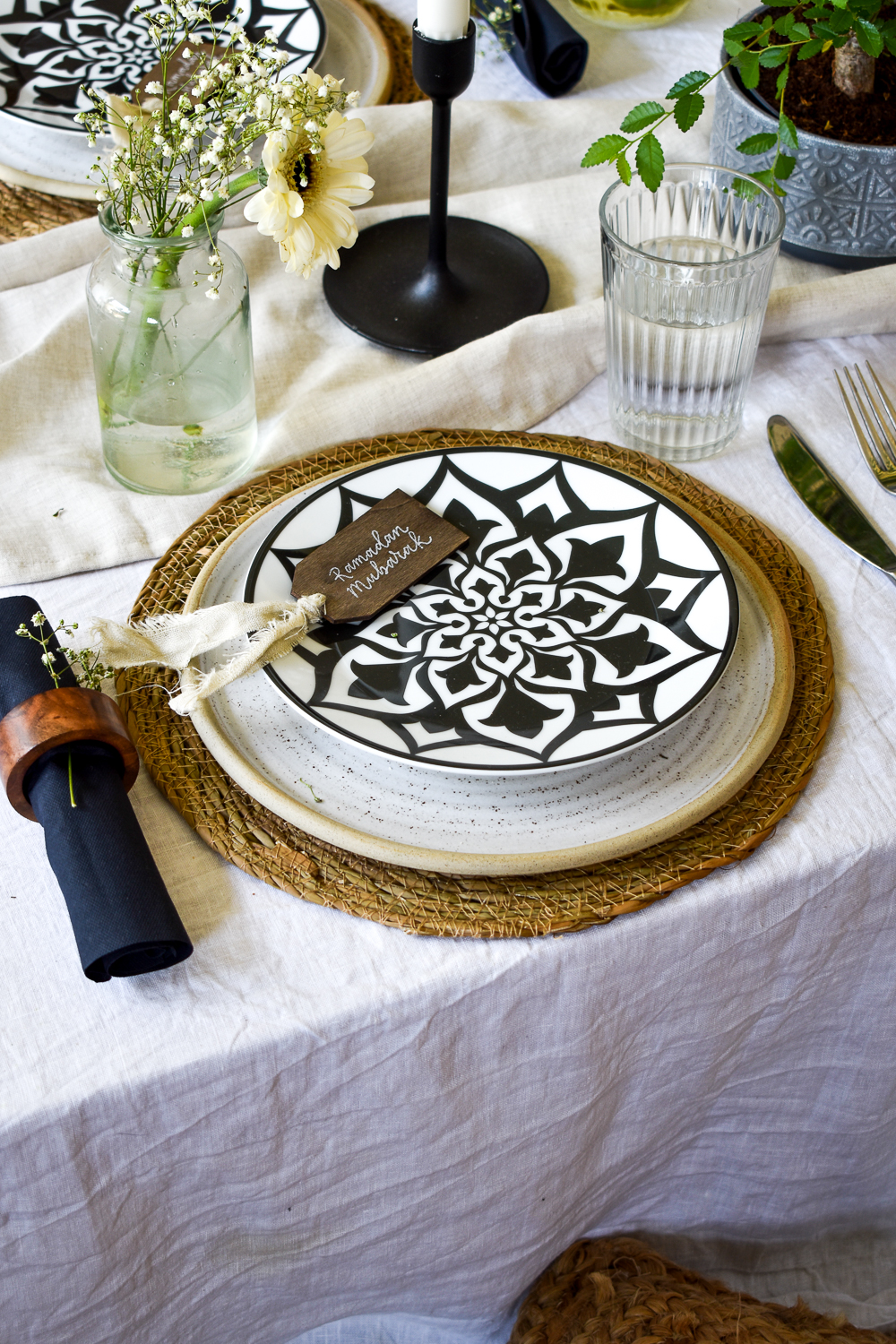 Place setting with jute charger, textured stone plate, black and white smaller plate on top with place card.