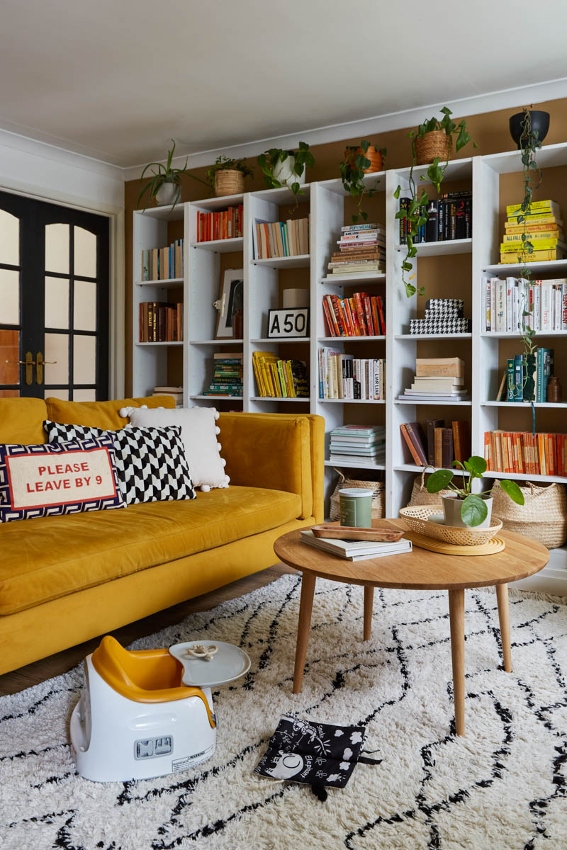 living room with bookcase wall, yellow sofa, and round coffee table