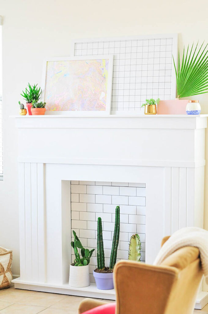 fake fireplace with subway tile interior and potted cactus sitting on the hearth