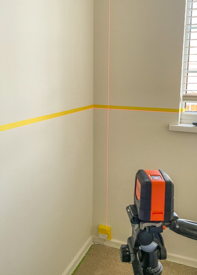 image of a laser level on a wall vertically to help create the simple panel wall effect