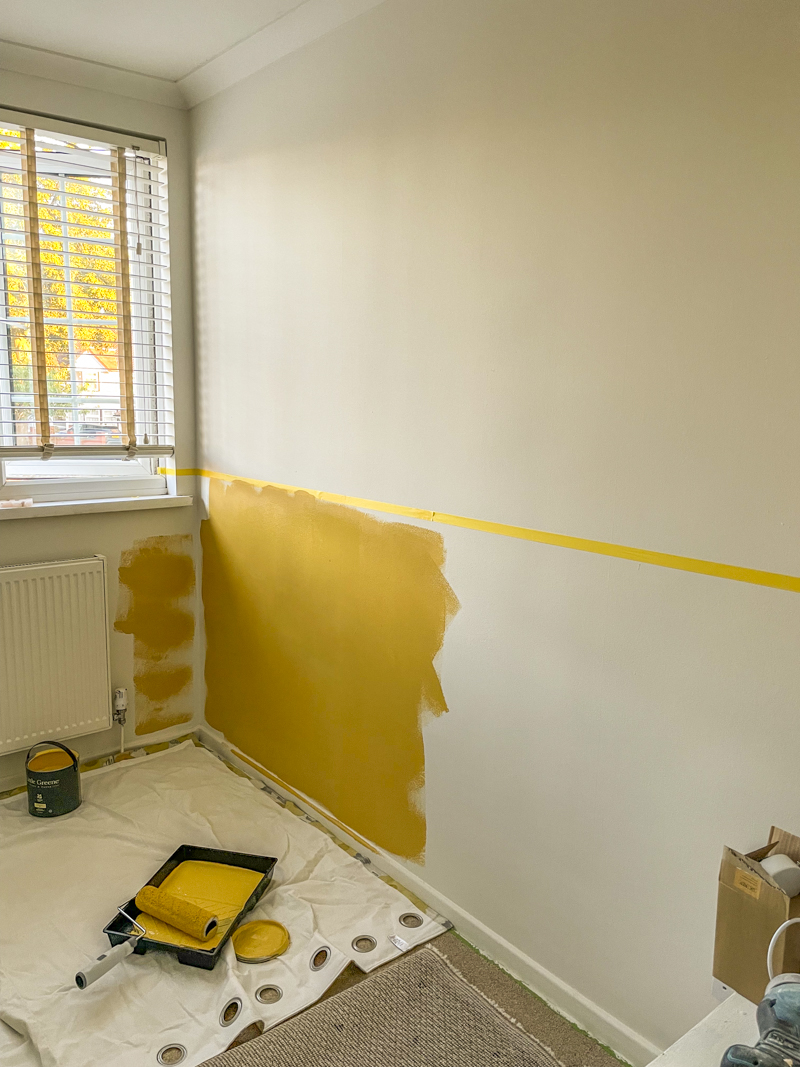 the start of a half painting wall in a warm, golden yellow. The black of the man cave office is no more as it has been repainted a warm white