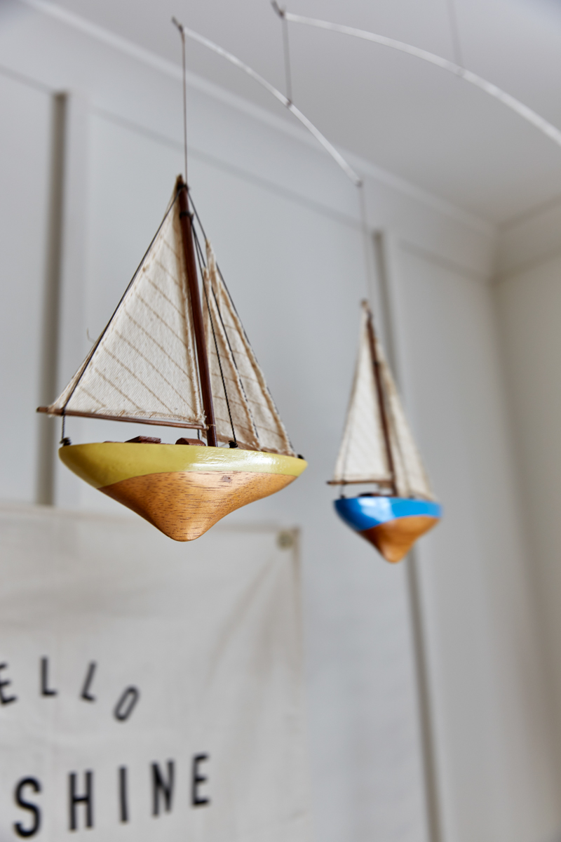 A close up of the boat hanging mobile. Little wooden boats of yellow and blue with canvas striped sails