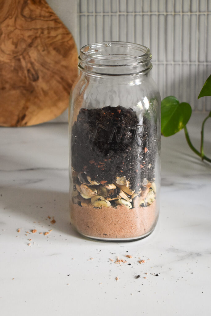 mason jar has sand, rocks/pebbles and finally some soil added in